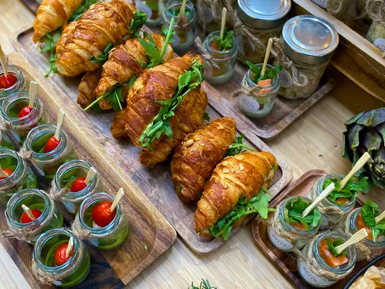 A platter of filled croissant rolls with garnish, on wooden boards